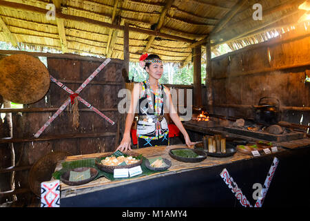 Jeune femme portant des décorations tribales de Bornéo proposant des aliments, mari Mari Cultural Village, Kota Kinabalu, Sabah, Bornéo, Malaisie Banque D'Images