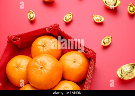 Groupe d'orange tangerine à motif chinois bac avec lingots sur rouge de table. Le nouvel an chinois.concep langue chinoise est riche lingot Banque D'Images