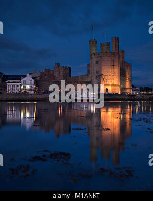 Château de Caernarfon sur la côte nord du Pays de Galles dans la nuit avec des reflets dans la mer Banque D'Images