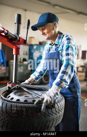 Senior female mechanic repairing une voiture dans un garage. Banque D'Images