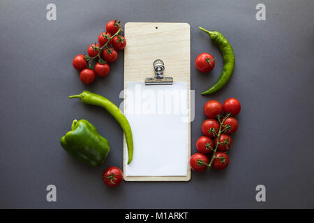 Vue de dessus de divers piments verts et tomates mûres avec feuille de papier blanc sur gris Banque D'Images