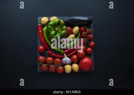 Vue de dessus les tomates mûres fraîches, poivrons, l'ail, l'aubergine et les pommes de terre sur le bord de l'ardoise Banque D'Images