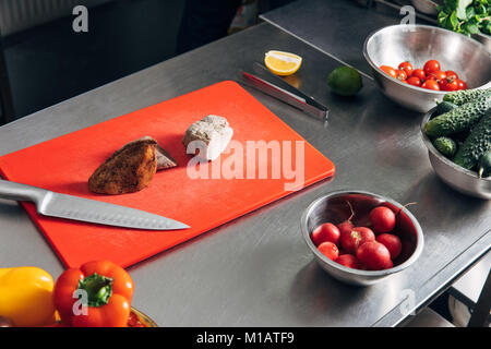 Viandes en tranches sur une planche à découper avec des légumes dans une cuisine de restaurant Banque D'Images