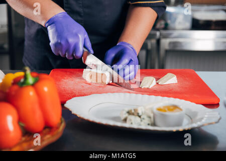 Cropped shot of chef slicing pour fromage plateau de fromages Banque D'Images