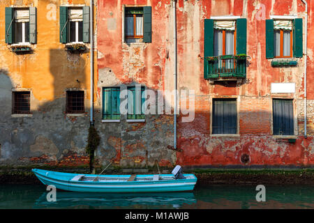 Voile sur petit canal amarré contre l'ancienne maison de briques colorées à Venise, Italie. Banque D'Images