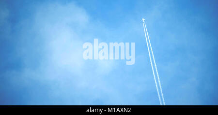 L'avion blanc volant dans le ciel et de laisser les pistes dans les nuages. Banque D'Images