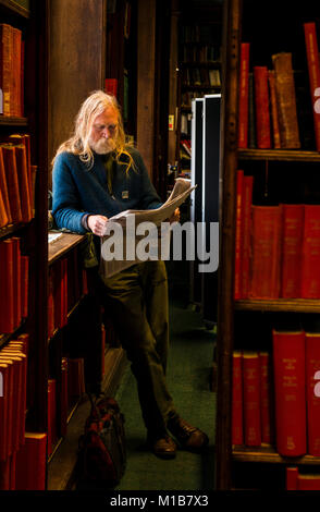 Man reading newspaper in library Banque D'Images