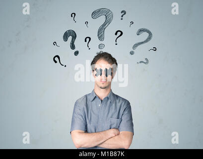 Jeune homme avec du ruban adhésif d'interrogation des yeux symboles autour de sa tête Banque D'Images