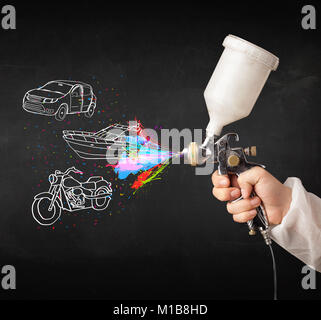 L'homme à l'aérographe peinture en aérosol avec voiture, moto et bateau dessin sur fond sombre Banque D'Images