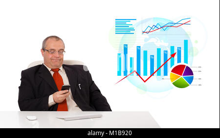 Businessman sitting at desk avec statistique et tenant une mobilephone, isolated on white Banque D'Images