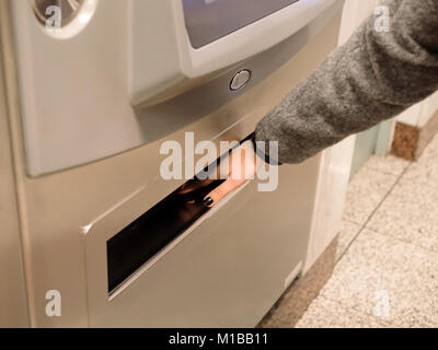 Main de la jeune fille prendre une pièce à partir d'un distributeur automatique de la station de métro à Athènes, Grèce Banque D'Images