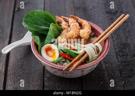 Soupe aux nouilles et fruits de mer épicés asiatiques avec des crevettes tempura et verts, fermer Banque D'Images