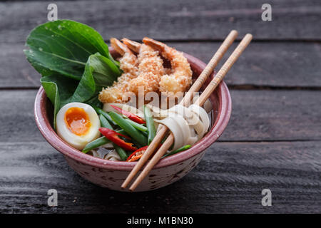 Soupe de nouilles japonais surmonté de crevettes tempura, l'oeuf et les verts, fermer Banque D'Images