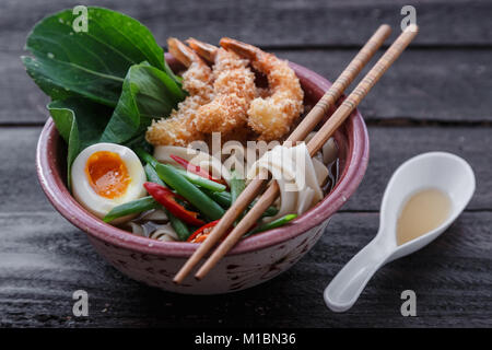 Soupe de nouilles japonais surmonté de crevettes tempura, l'oeuf et les verts, fermer Banque D'Images