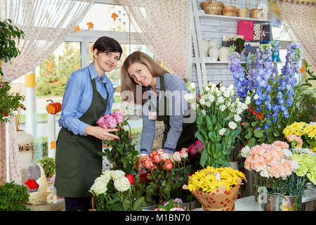 Les vendeurs de fleurs des femmes. Deux jeunes femmes travaillant dans le magasin de fleurs et de profiter de belles fleurs. Banque D'Images