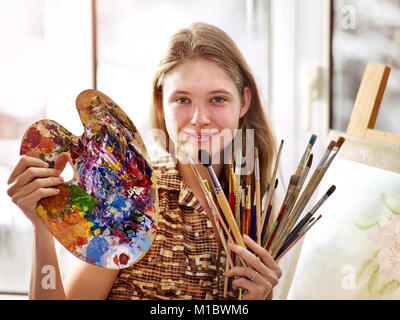 Artiste peinture sur chevalet dans Studio. Les peintures de fille avec un pinceau. Banque D'Images