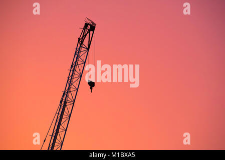 La construction d'une flèche sur un chantier découpé sur un coucher du soleil orange à Sydney, Australie Banque D'Images