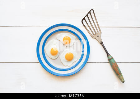 Oeufs de caille frit sur un cornishware plaque avec une spatule vintage d'en haut Banque D'Images