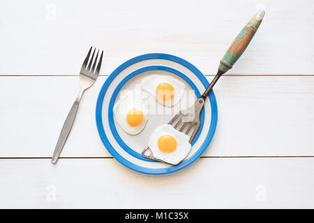 Oeufs de caille frit sur un cornishware plaque avec une spatule et fourchette vintage d'en haut Banque D'Images