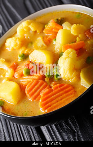 Curry végétarien à partir de pommes de terre, carottes, choux-fleurs, pois, tomates close-up dans un bol sur la table verticale. Banque D'Images