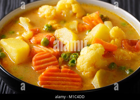 Curry de légumes Pommes de terre, carottes, choux-fleurs, pois, tomates close-up dans un bol sur la table horizontale. Banque D'Images