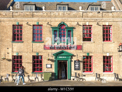 Une jeune femme l'organisation des employés à l'extérieur de la chaises Queen's Head pub / restaurant en centre-ville de Peterborough, Cambridgeshire, Angleterre, Royaume-Uni. Banque D'Images