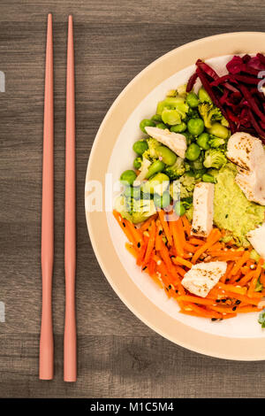 Style asiatique Salade de poulet cuits au feu avec du choux rouge Carottes Edamame Beans et l'hoummos contre un arrière-plan en bois foncé Banque D'Images