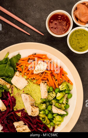 Style asiatique Salade de poulet cuits au feu avec du choux rouge Carottes Edamame Beans et l'hoummos contre un arrière-plan de carrelage noir Banque D'Images