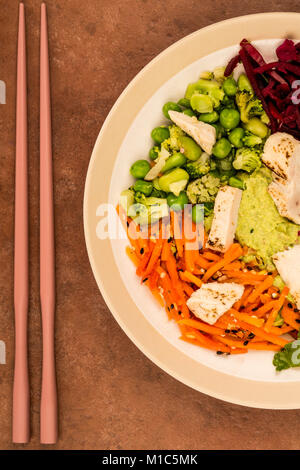 Style asiatique Salade de poulet cuits au feu avec du choux rouge Carottes Edamame Beans et l'hoummos contre un arrière-plan de tuile rouge Banque D'Images