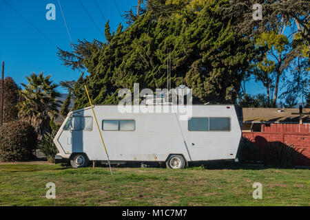 Un livre blanc du transitoire RV équipé d'une antenne satellite et à l'AC est garée sur une bande d'herbe à Goleta, CA. Banque D'Images
