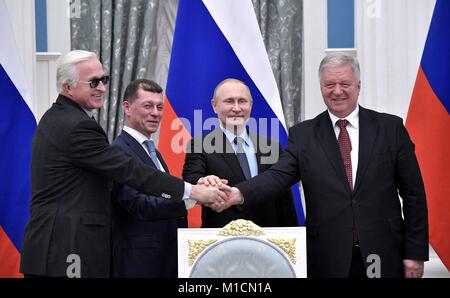 Fédération des Syndicats indépendants de la Russie le Président Mikhail Shmakov, droite, serre la main du Président de l'Union des industriels et entrepreneurs de Alexander Shokhin, gauche, au cours d'une cérémonie de signature entre la Fédération des syndicats, les employeurs et le gouvernement russe le président russe Vladimir Poutine, centre, et ministre du Travail et de la Protection Sociale Maxim Topilin inscrivez-vous en Janvier 29, 2018 à Moscou, Russie. Banque D'Images