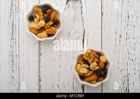 Vue de dessus les amandes et les noix de cajou et aux raisins secs et et les bleuets sur deux plats blanc Banque D'Images