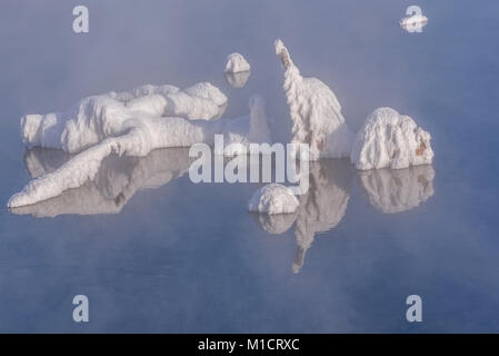 Belle vue hiver abstrait avec un lac, des figures de brindilles dans la gelée blanche sur l'eau, les reflets et le brouillard sur la surface de l'eau Banque D'Images