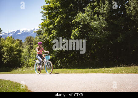 Girl wearing sécurité, casque vélo sur route Banque D'Images