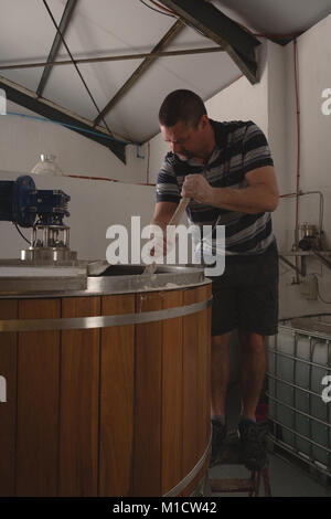 Travailleur homme remuant dans gin distillery Banque D'Images