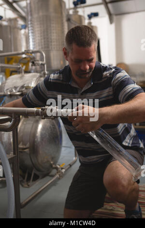 Travailleur homme remplissant en éprouvette de gin distillery Banque D'Images