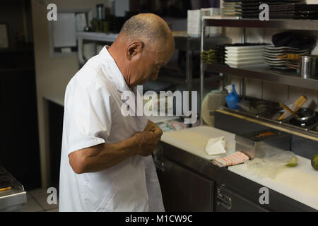 Senior chef de porter son uniforme dans la cuisine Banque D'Images