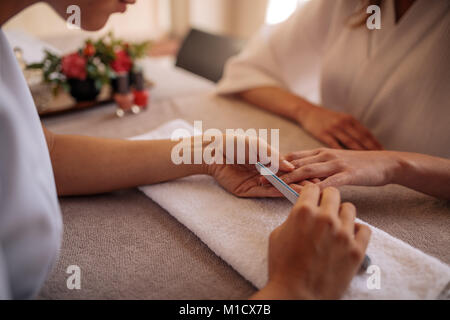 Mains de la manucure ongles le dépôt de femme client avec un tampon blanc in nail salon. Se concentrer sur les mains de manucure ongles en forme de femme Banque D'Images