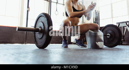 La jeune femme des mains mains avec de la craie en poudre, de la préparation à la formation d'haltères dans une salle de sport. Jeune athlète étant prêt pour la formation de plusieurs monter gy Banque D'Images