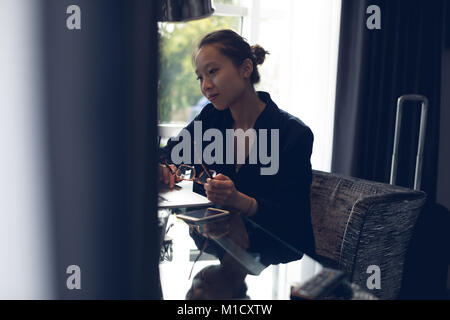 Thoughtful woman sitting at table avec des lunettes Banque D'Images