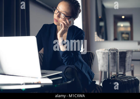 Woman talking on mobile phone while using laptop Banque D'Images