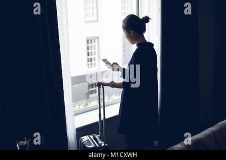 Woman using mobile phone in hotel room Banque D'Images