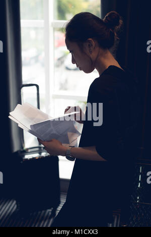 Femme lisant des documents dans chambre d'hôtel Banque D'Images