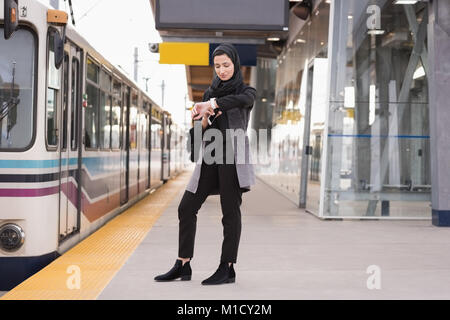 Femme en hijab en utilisant smartwatch Banque D'Images