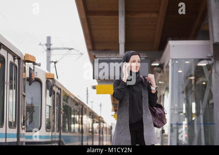 Femme en hijab talking on mobile phone Banque D'Images