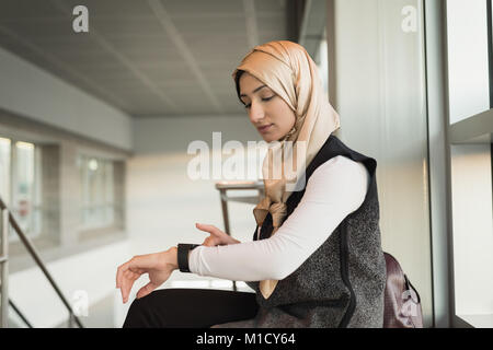 Femme en hijab en utilisant smartwatch Banque D'Images