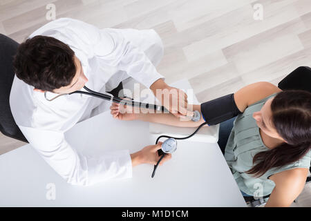 Portrait de jeune homme médecin Contrôle de pression sanguine de Female Patient In Clinic Banque D'Images