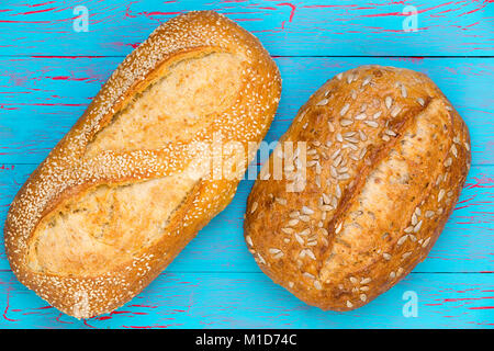 Deux pains délicieux pain croûté frais vu du dessus, l'un avec le tournesol et l'autre avec les graines de sésame sur une ba en bois peint bleu craquelé Banque D'Images