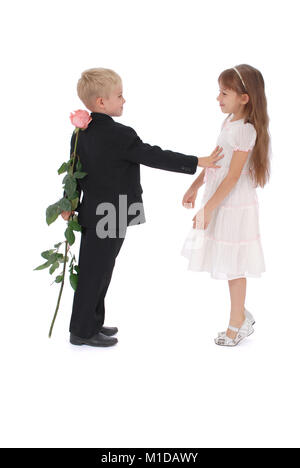 Le garçon se cache une rose derrière un retour. La fille veut voir une rose. Sur un fond blanc Banque D'Images