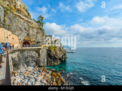 Les touristes à pied le chemin et entrer dans le tunnel, sur la côte de Monterosso al Mare, Cinque Terre, avec le château de Monterosso dans vue sur la mer Banque D'Images